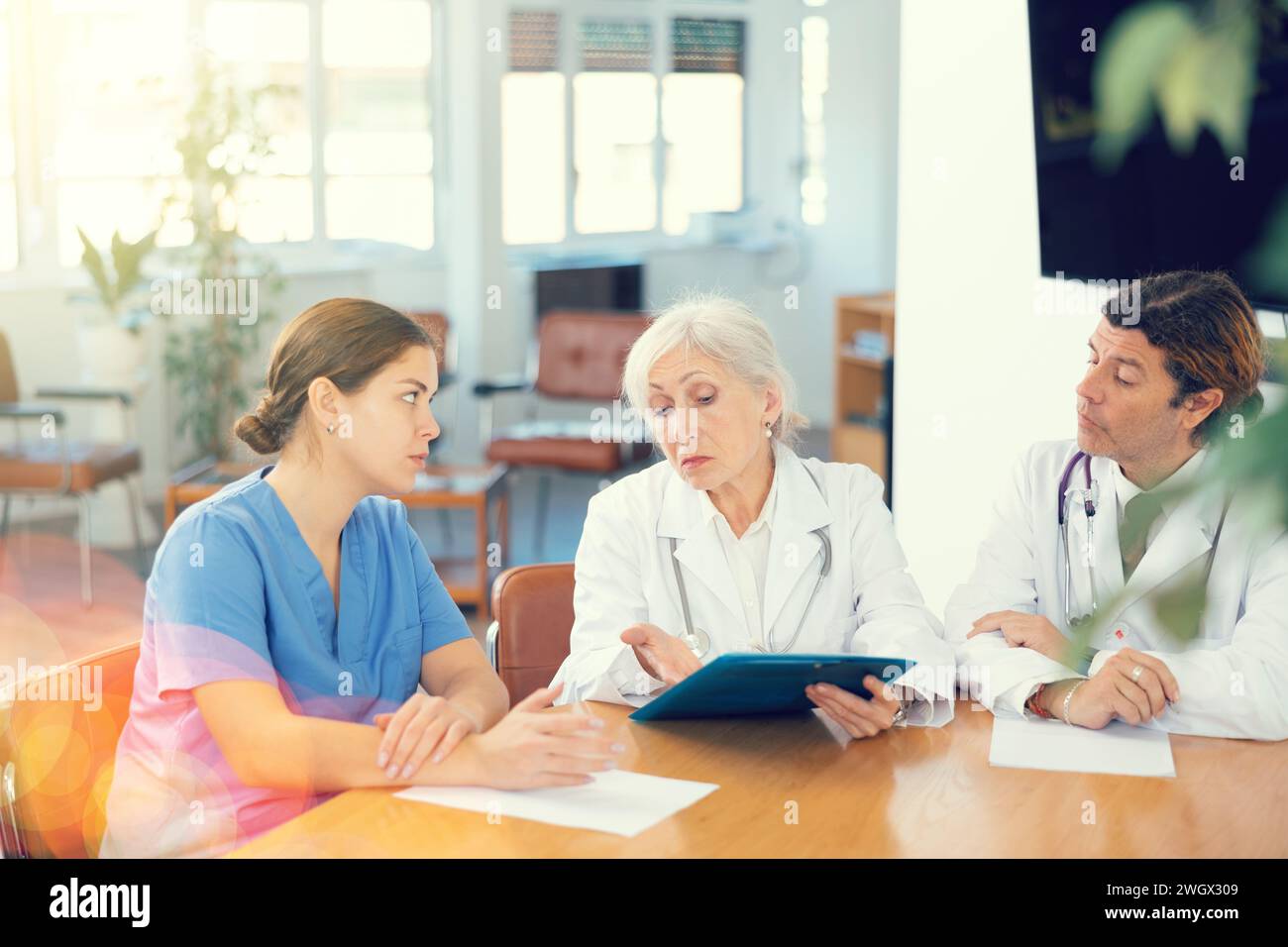 Senior female head doctor conducting medical council with colleagues Stock Photo