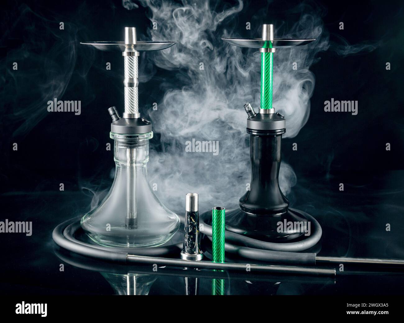 Two modern hookahs with smoke on a black mirror background. Stock Photo