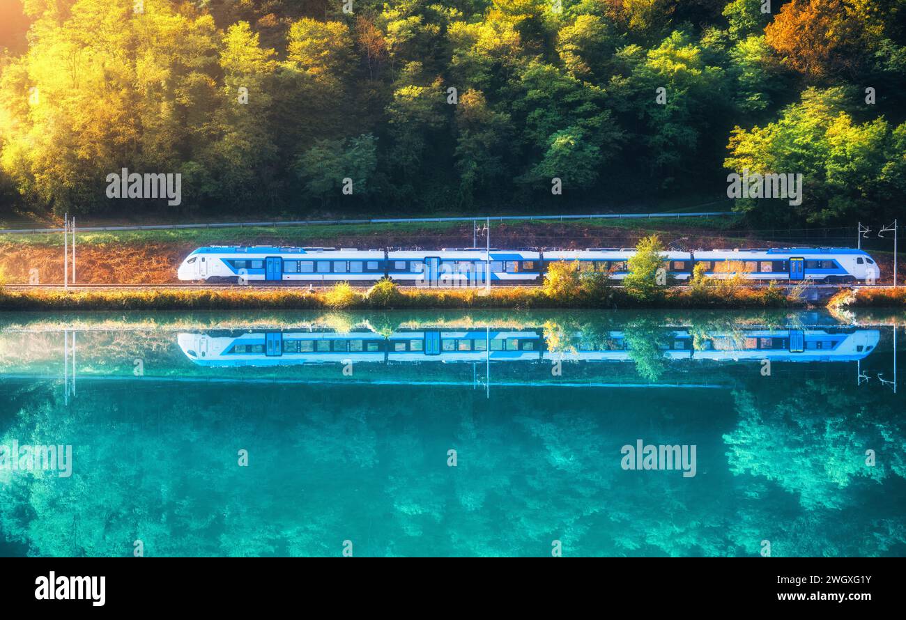 Blue speed train and river in alpine mountains at sunrise Stock Photo ...