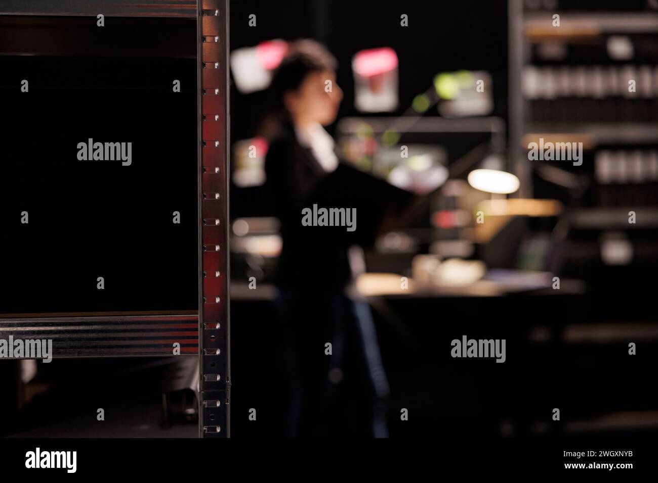 Selectiv focus of metallic storage full with confidential files, in background police officer analyzing investigations report. Private detective working overhours at criminal case in arhive room Stock Photo