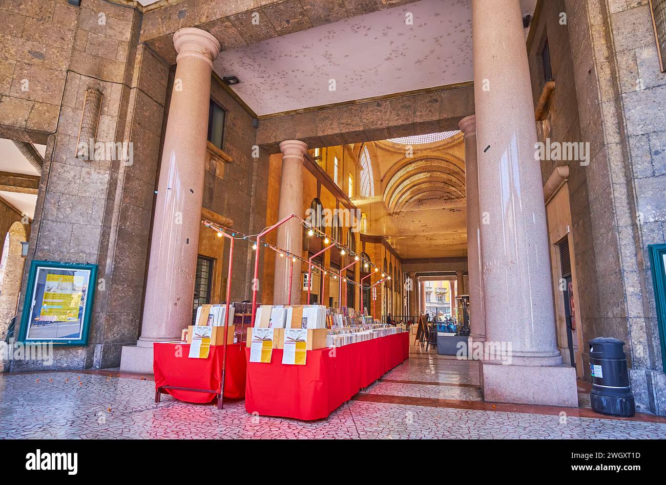 CREMONA, ITALY - APRIL 6, 2022: The stone hall of Galleria XXV Aprile with stalls of book market and tall massive stone columns, Cremona, Italy Stock Photo