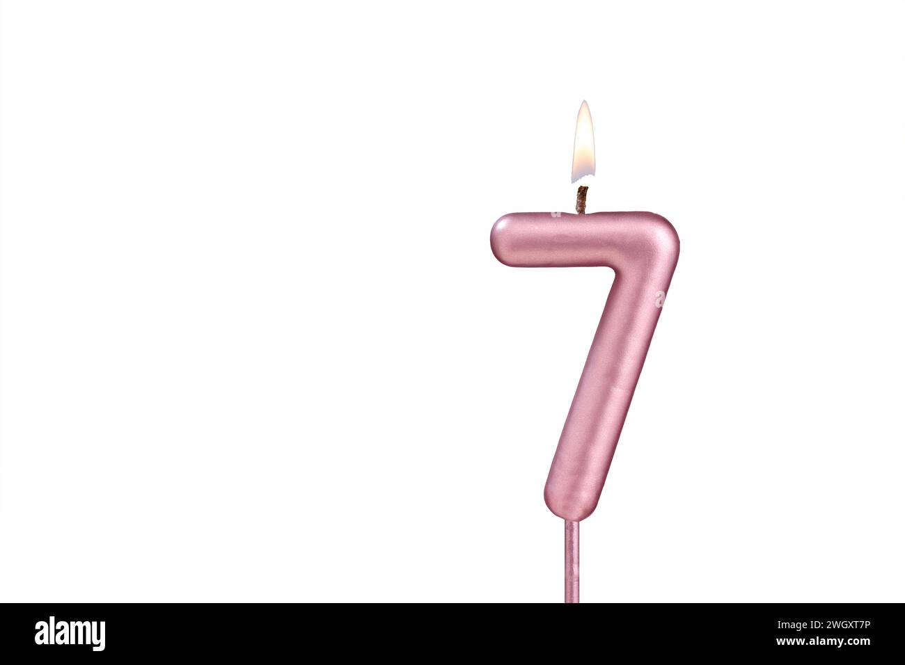 Candle number 7 Lit birthday candle on white background Stock Photo