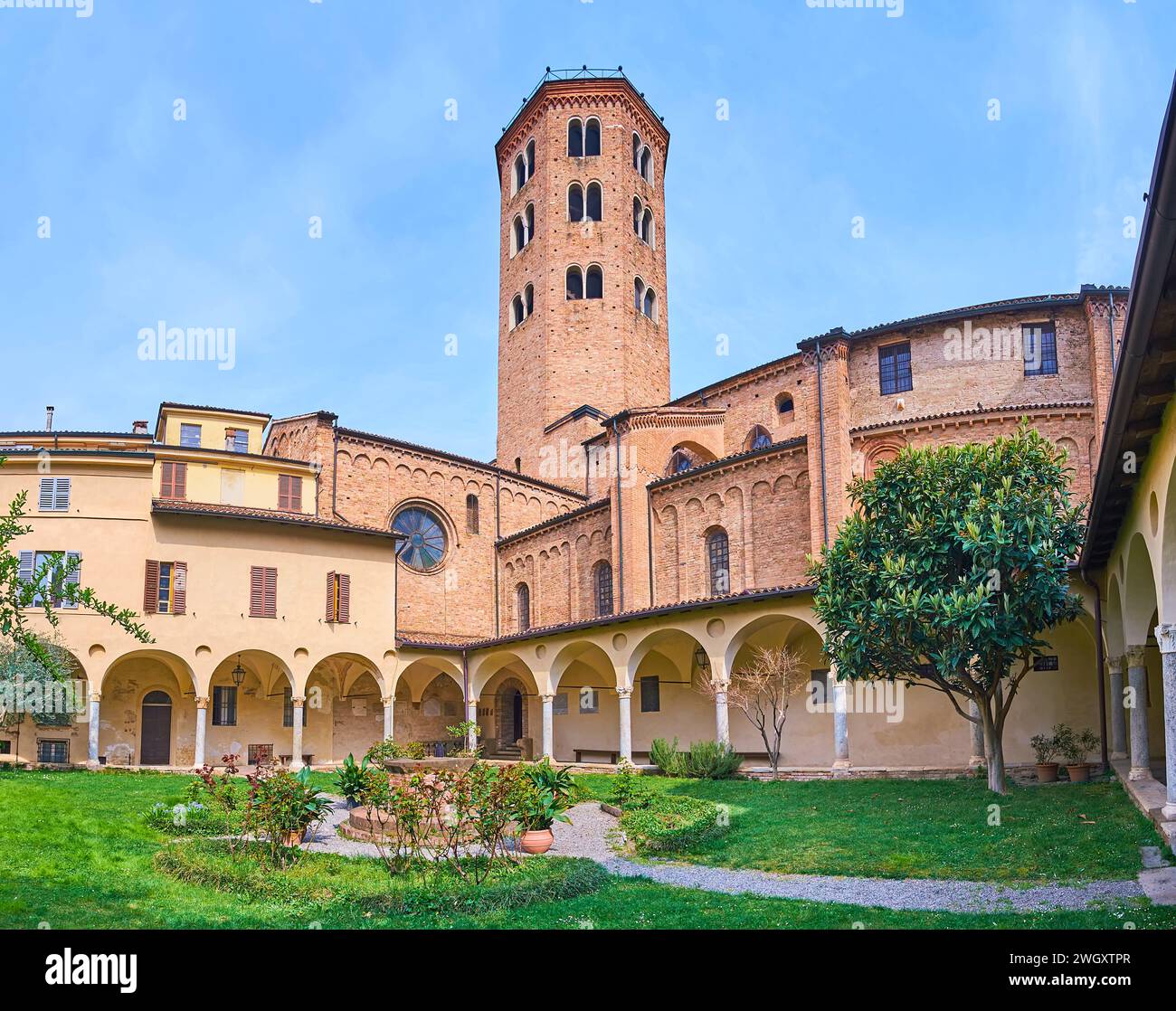 The small scenic medieval courtyard of St Antoninus Basilica with a nice green garden, arched galleries and a view on campanile (bell tower) of the ch Stock Photo