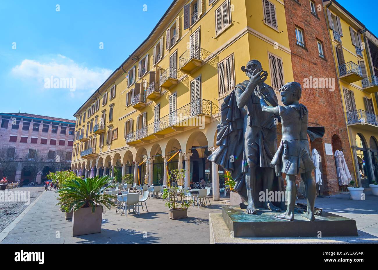 CREMONA, ITALY - APRIL 6, 2022: The statue of Antonio Stradivari against historic house with outdoor dining, Cremona, Italy Stock Photo