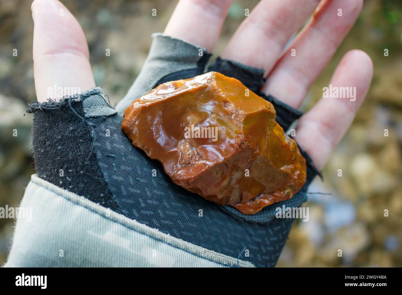 Red-brown flint with traces of retouching on the edge, Stone Age flint tool in hand Stock Photo