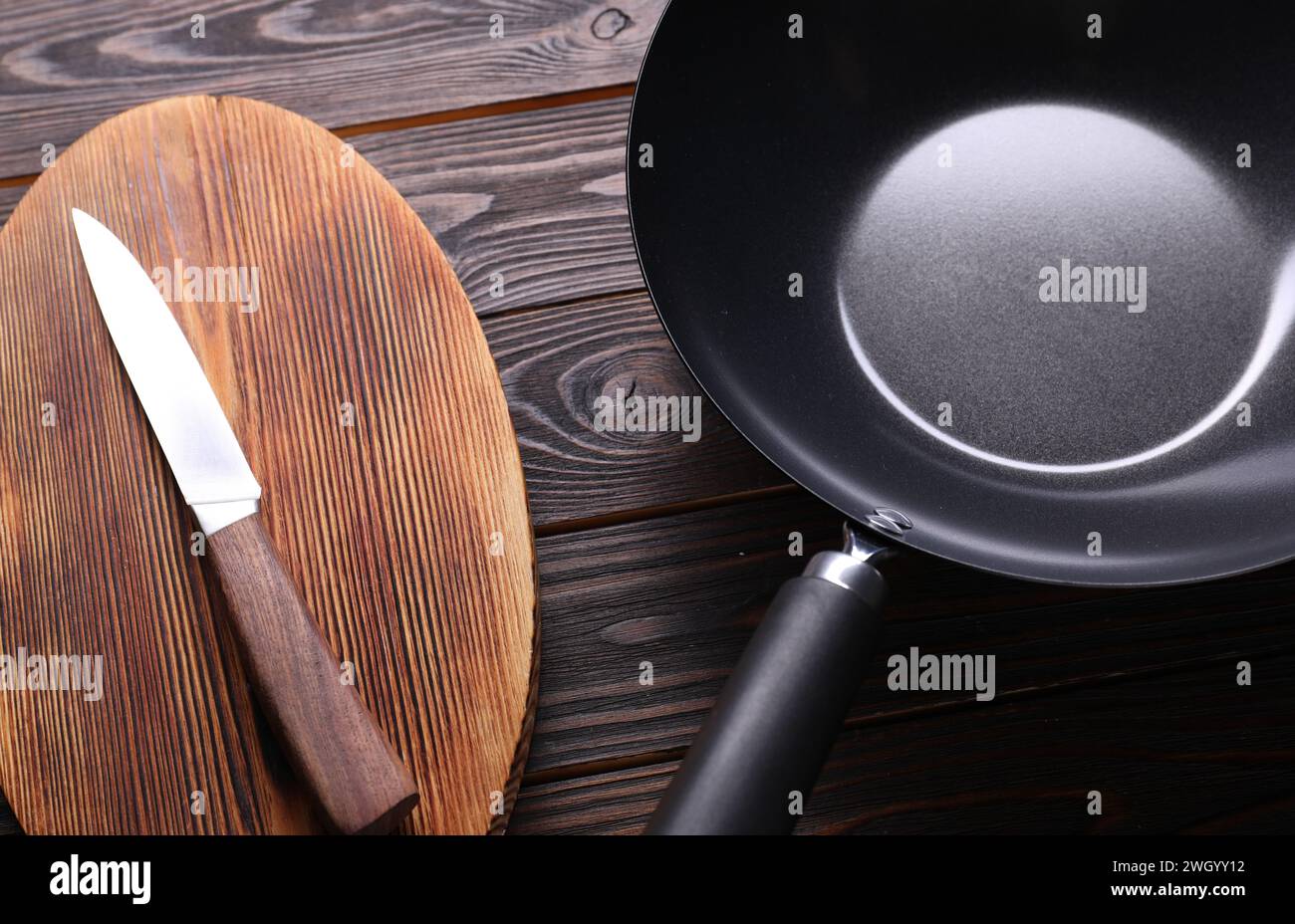 Empty iron wok, knife and cutting board on wooden table Stock Photo Alamy