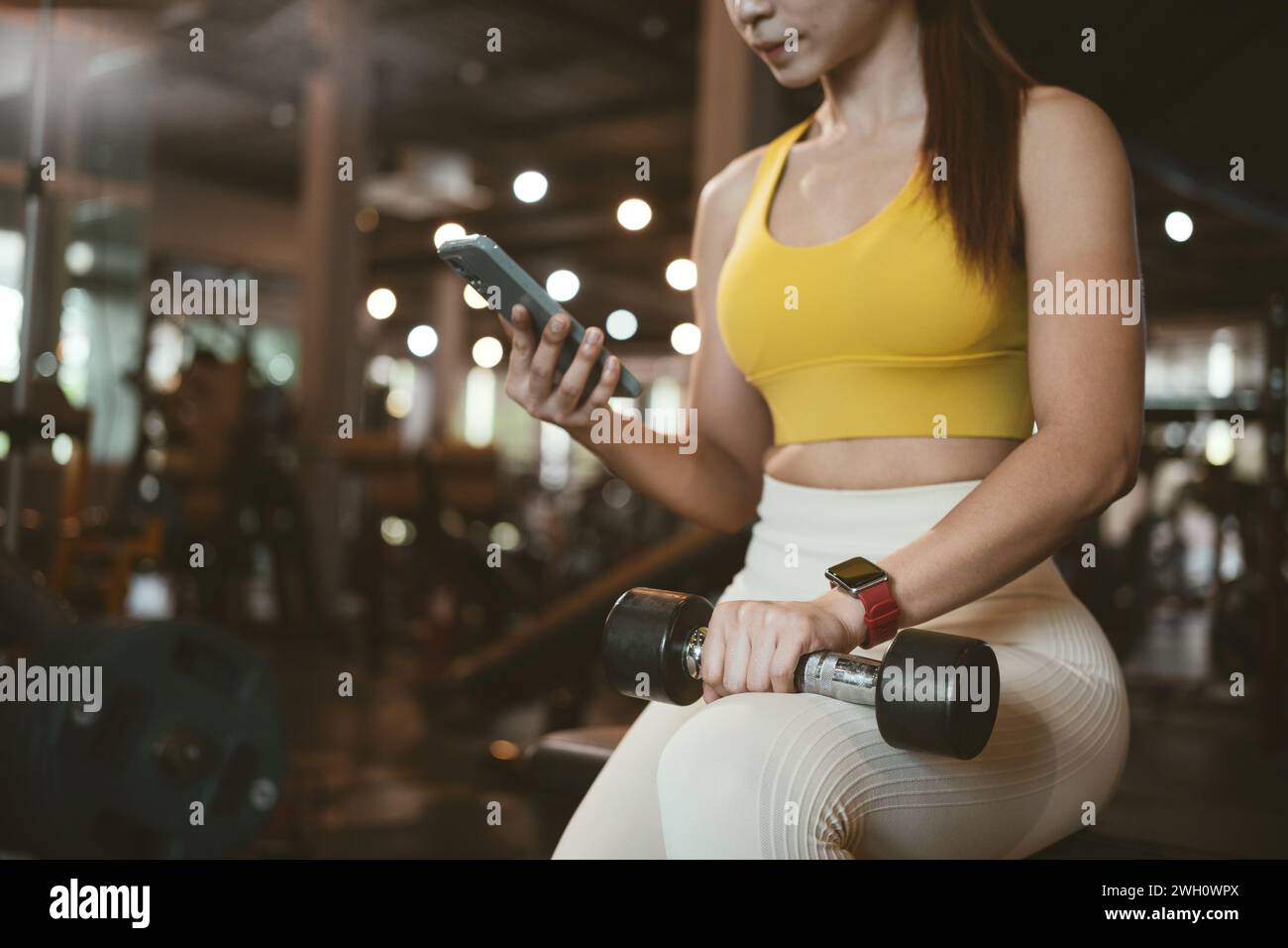 Young aisan woman using a phone in the gym. Stock Photo