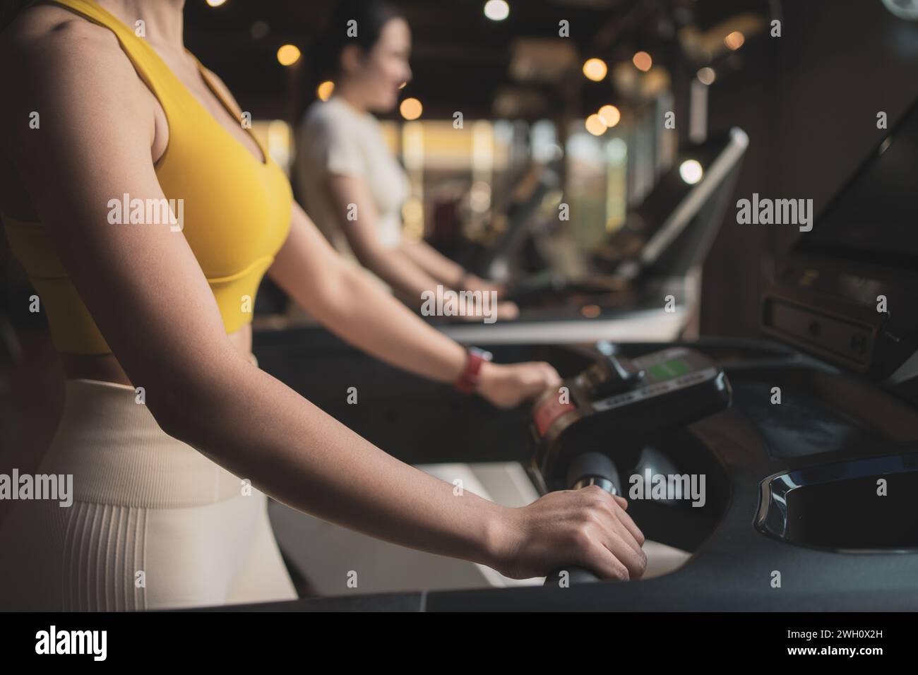 Two young woman are jogging on treadmill during her sports training in a gym. Stock Photo