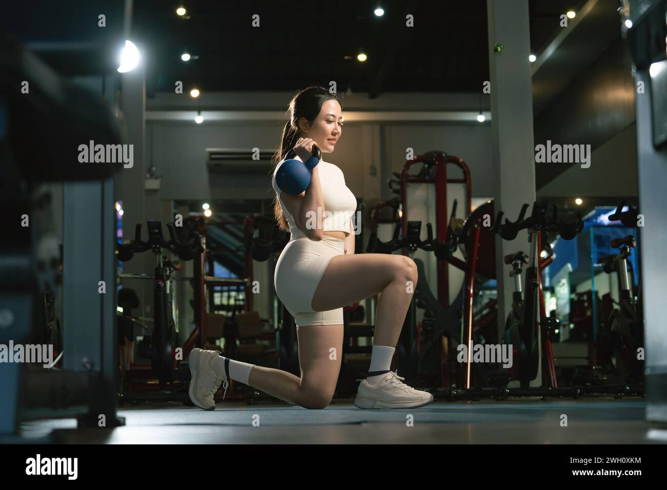 Young woman exercise workout at gym fitness training sport with kettlebell weight lifting. Stock Photo