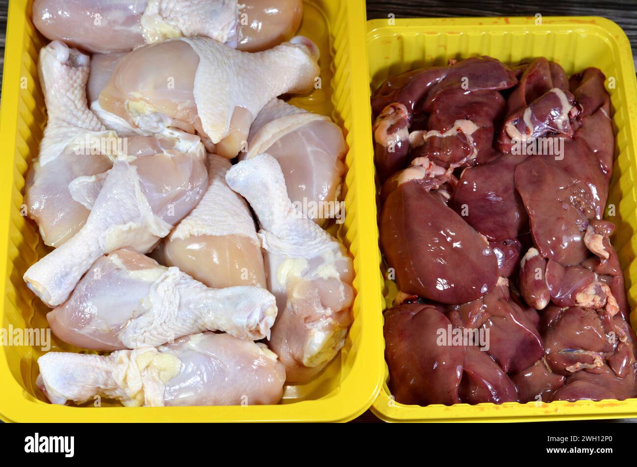 Raw chicken legs drumsticks hindquarter with skin and bones and fresh uncooked chicken livers, gizzards and hearts, selective focus of fresh liver, gi Stock Photo