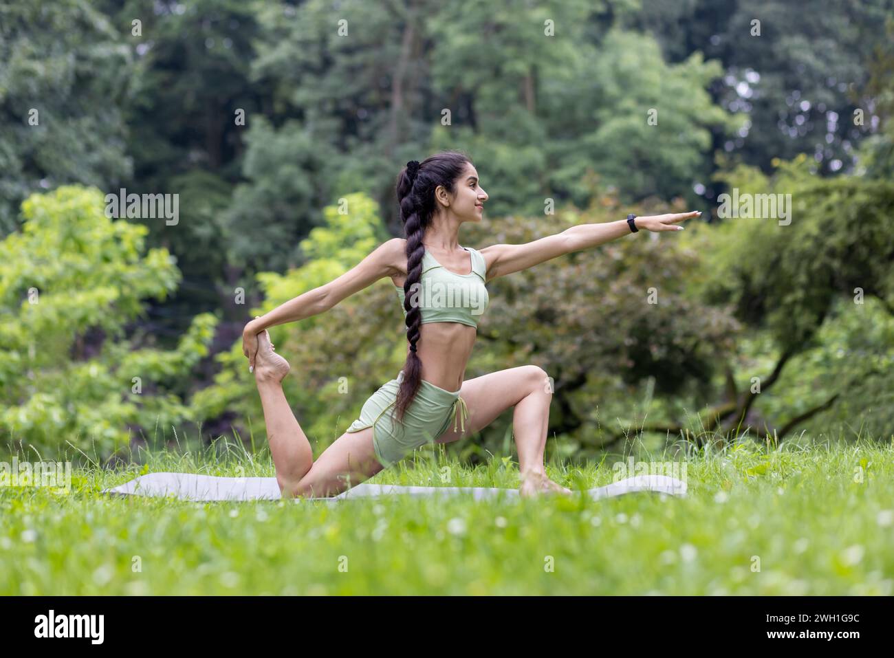 Happy smiling brunette woman has yoga exercises with fitness ball poses at  park with green grass, has cheerful expression, stays fit and healthy,  leads active lifestyle, has morning gymnastic 8241961 Stock Photo