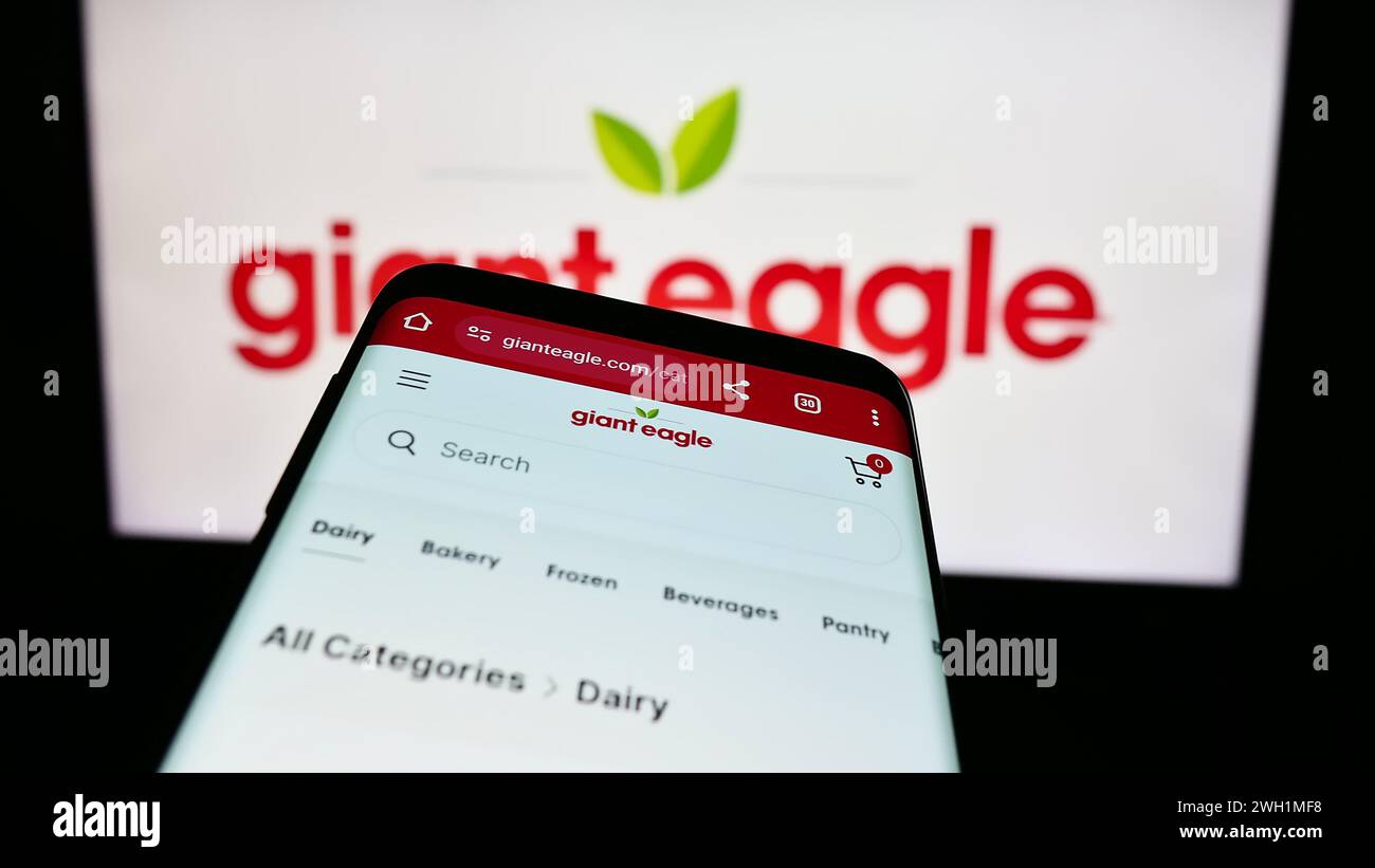 Mobile phone with website of US supermarket chain company Giant Eagle Inc. in front of business logo. Focus on top-left of phone display. Stock Photo