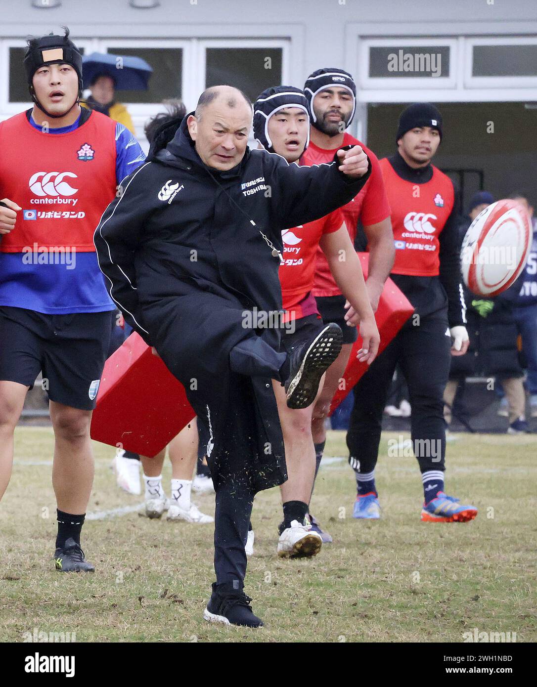 Japan rugby head coach Eddie Jones (2nd from L) kicks a ball during a training session in the