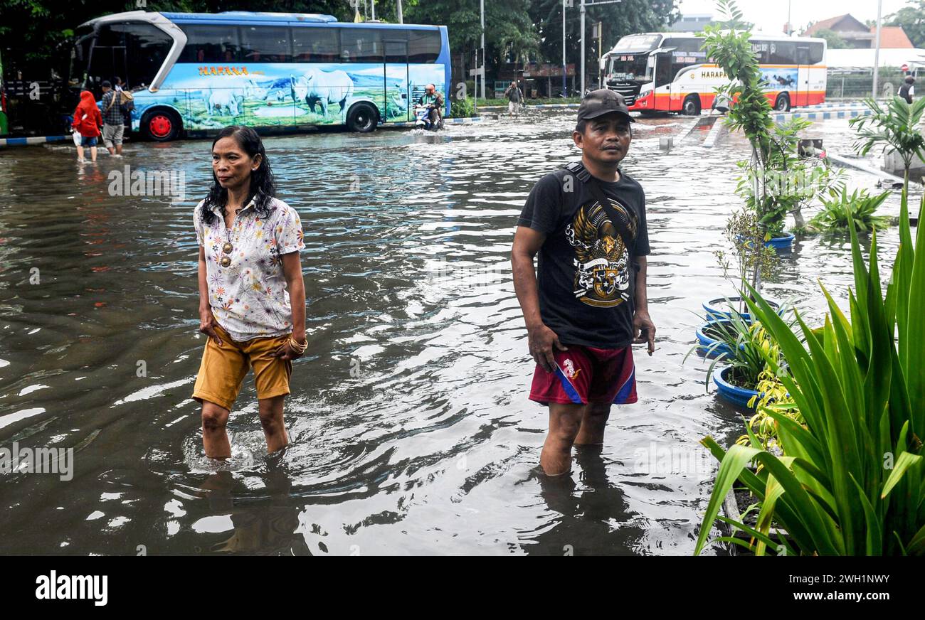 Sidoarjo, Indonesia. 7th Feb, 2024. People wade through flood water at Purabaya bus station in Sidoarjo, East Java, Indonesia, on Feb. 7, 2024. Credit: Sahlan Kurniawan/Xinhua/Alamy Live News Stock Photo