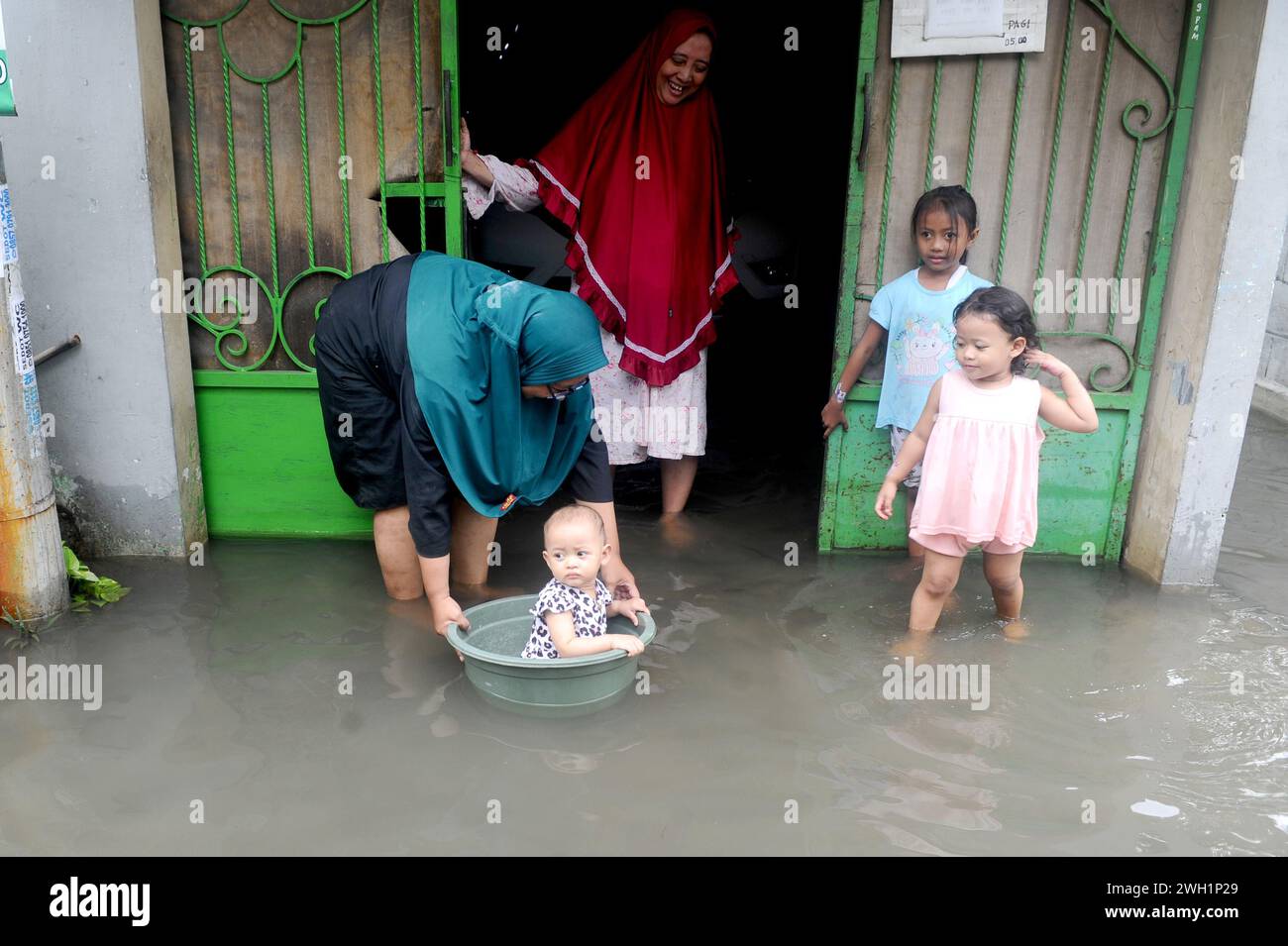 Sidoarjo, Indonesia. 7th Feb, 2024. A woman puts a baby in a basin on the flooded street in Sidoarjo, East Java, Indonesia, on Feb. 7, 2024. Credit: Sahlan Kurniawan/Xinhua/Alamy Live News Stock Photo