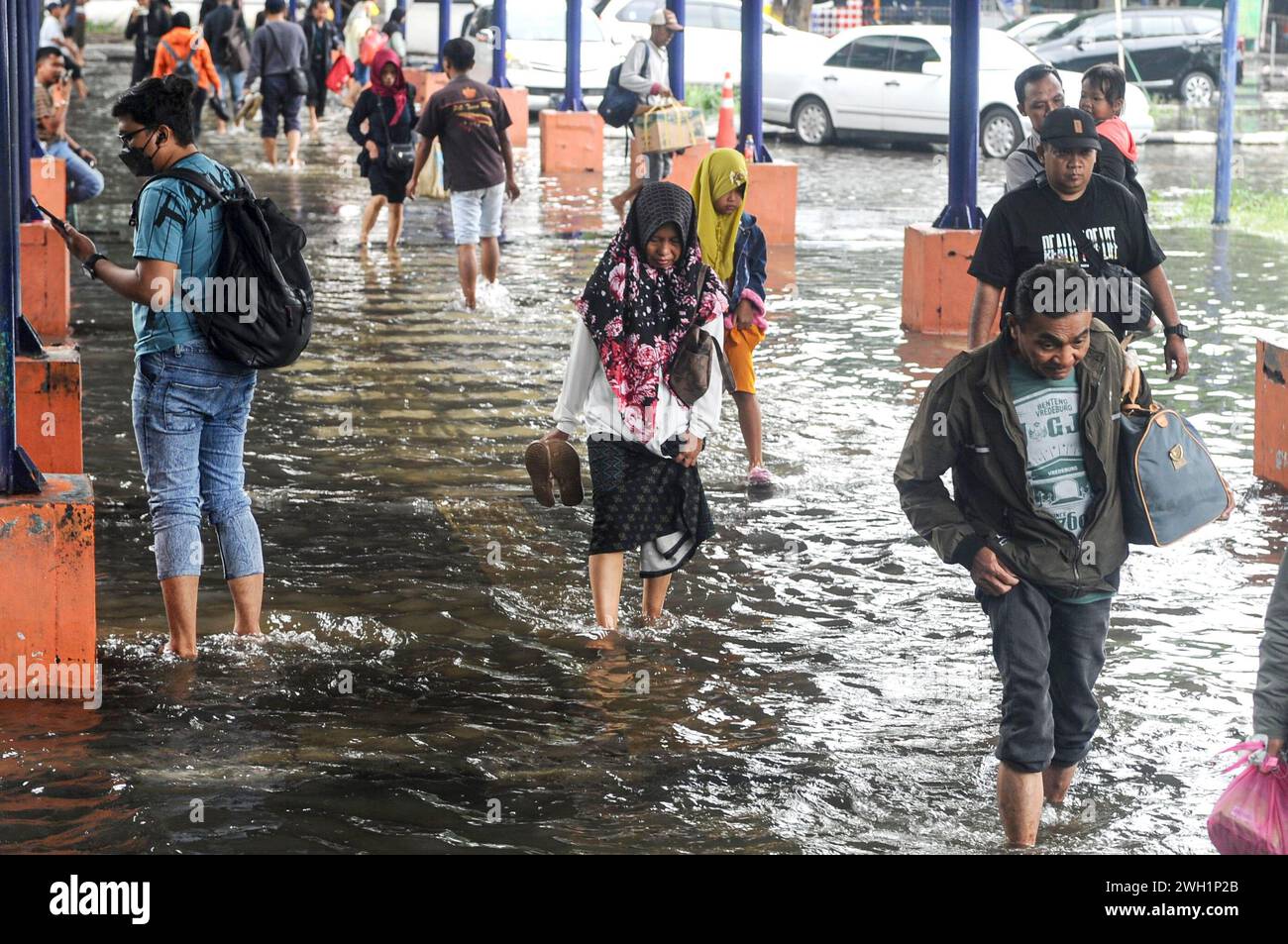 Sidoarjo, Indonesia. 7th Feb, 2024. Passengers wade through flood water at Purabaya bus station in Sidoarjo, East Java, Indonesia, on Feb. 7, 2024. Credit: Sahlan Kurniawan/Xinhua/Alamy Live News Stock Photo