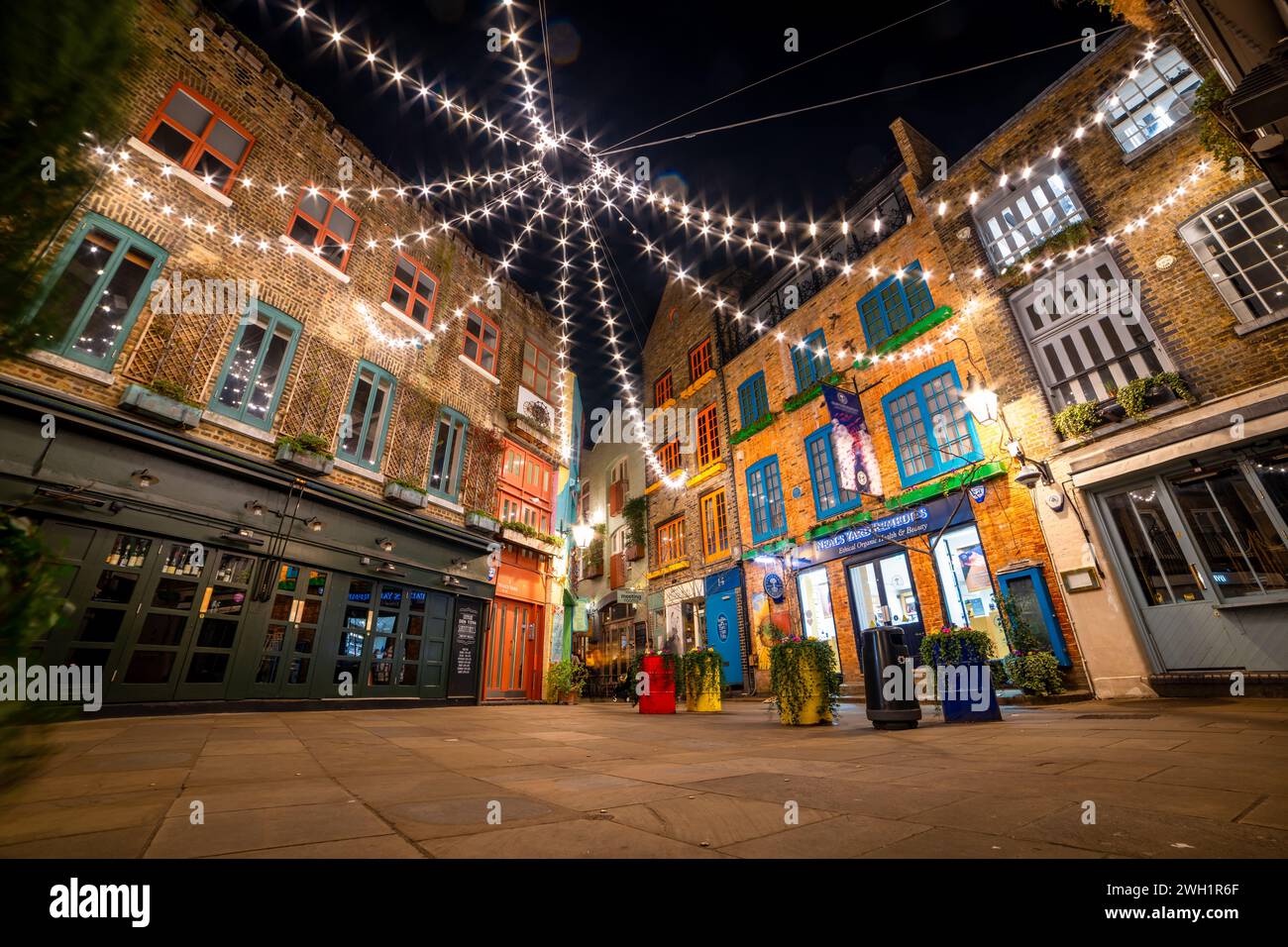 London. UK- 02.04.2024. A low, wide angle night time view of Neal's Yard showing the overhead lighting and Victorian warehouse architecture. Stock Photo
