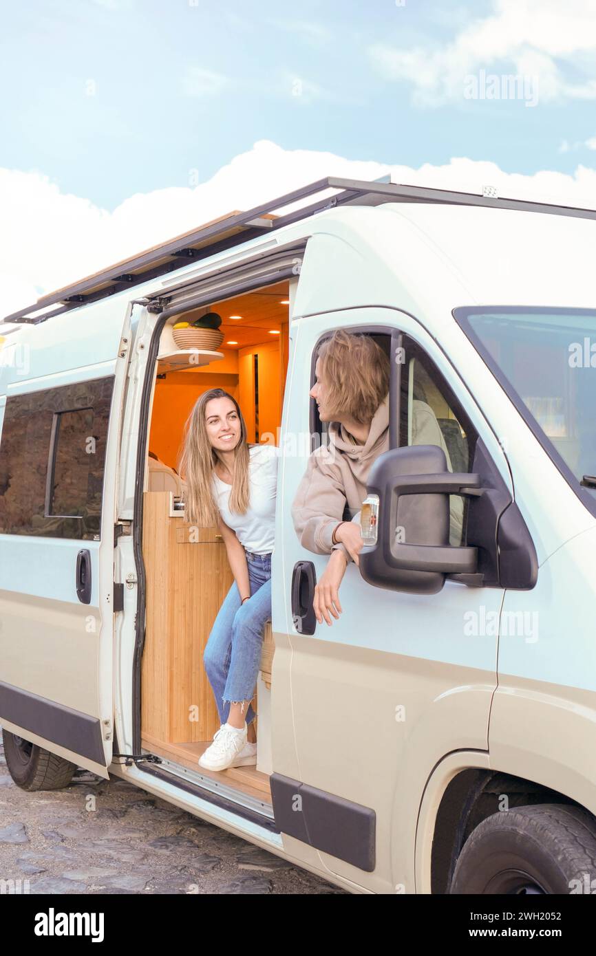 A young couple is seen cherishing a moment together inside their modern luxury campervan, symbolizing adventure and a carefree lifestyle. Stock Photo