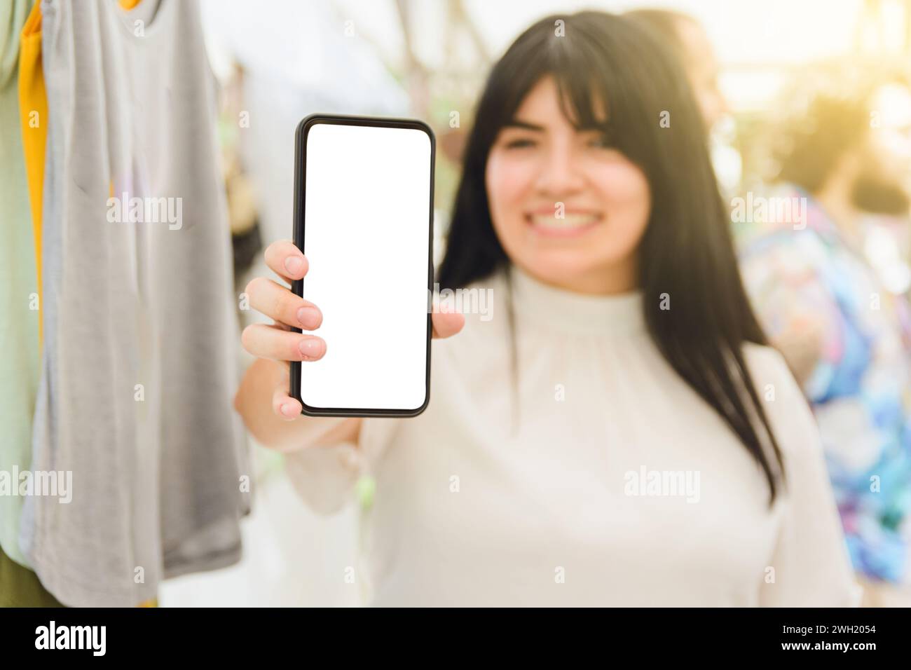 Happy smiling woman on blurred background holding mobile phone with blank screen, technology concept, copy space. Stock Photo