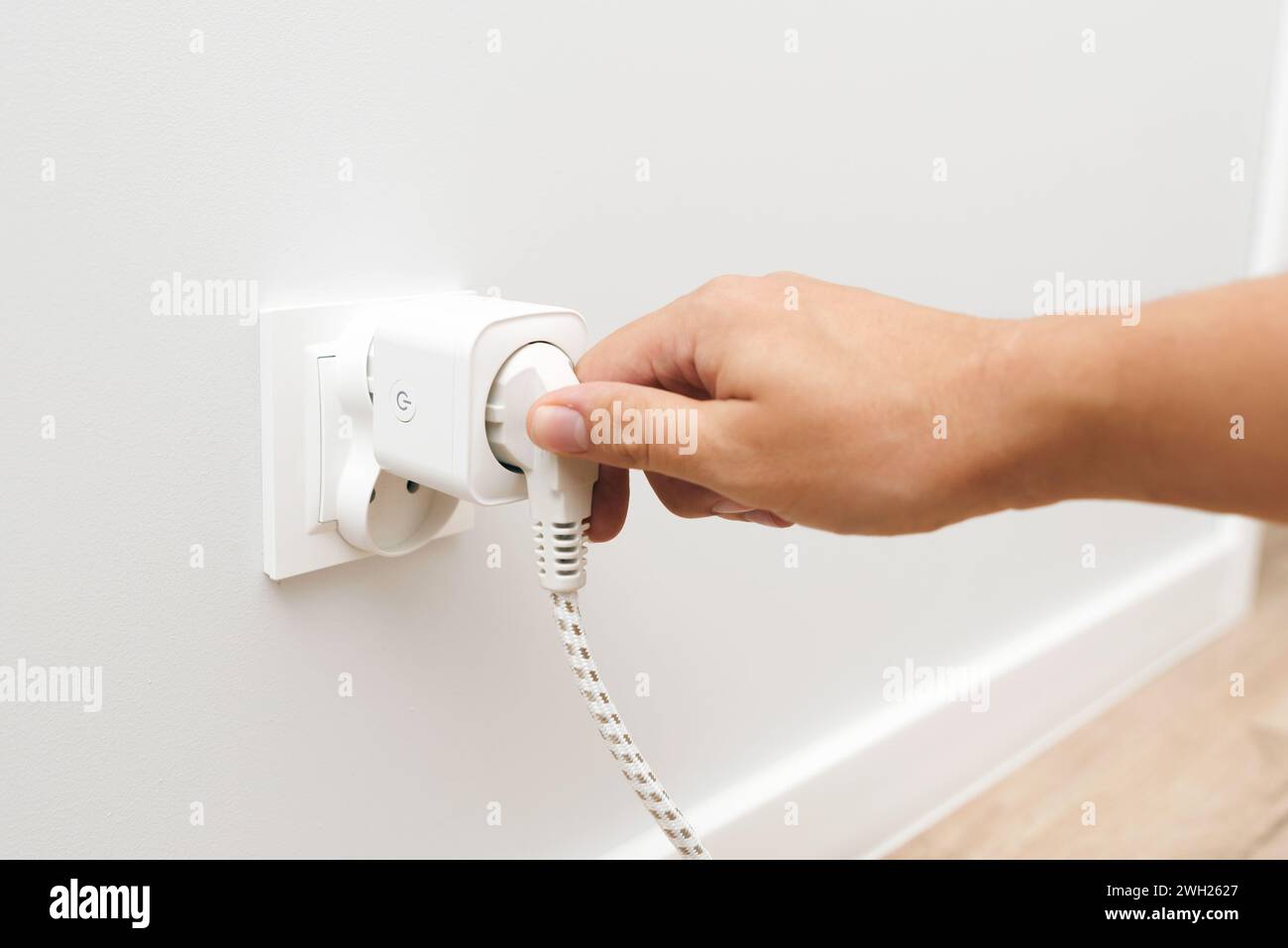 Man uses an electrical socket, smart plug into the socket. Control of electricity expenses Stock Photo