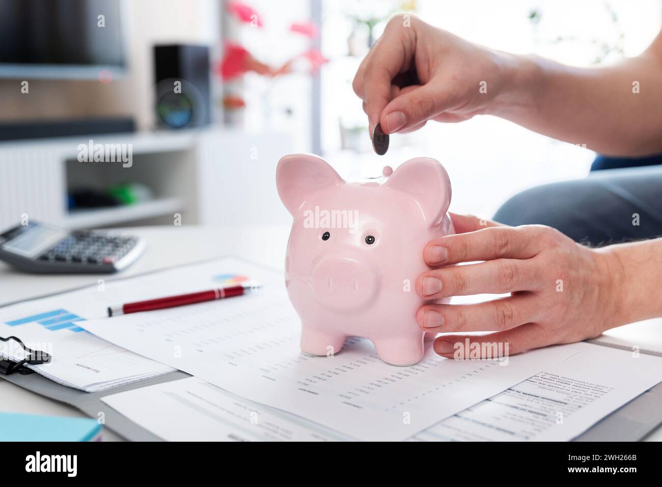 Savings concept with man putting coin into piggy bank Stock Photo - Alamy