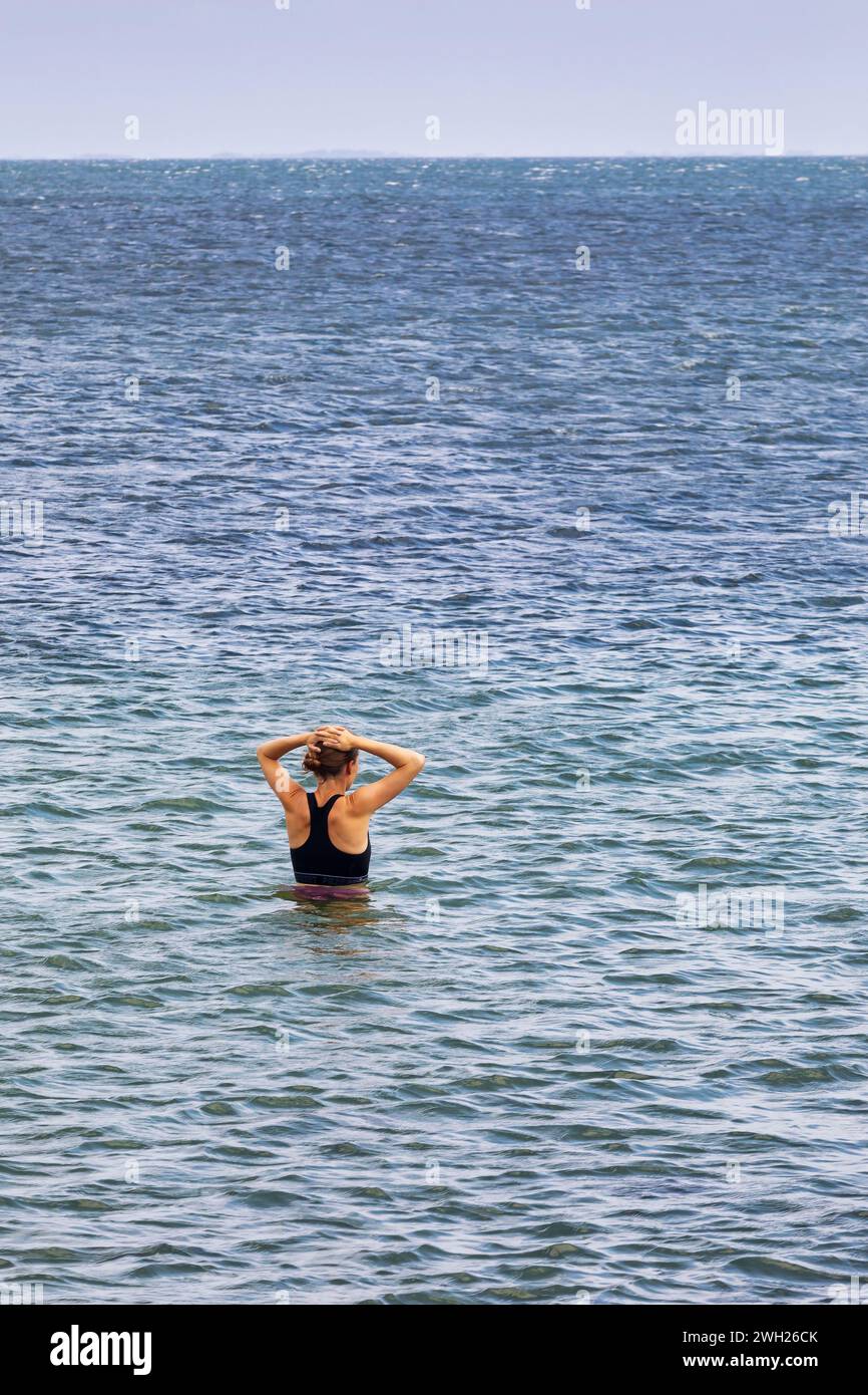 A woman is in the water looking out to sea on Amager beach in Copenhagen Stock Photo