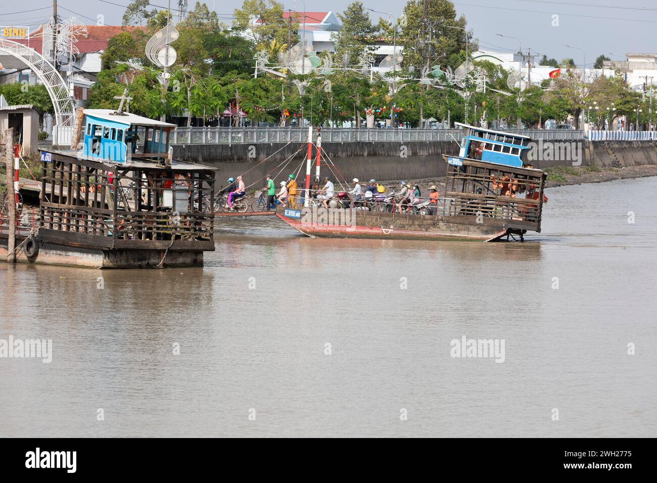 Travellers disembarking a small cross river ferry in the Mekong Delta ...
