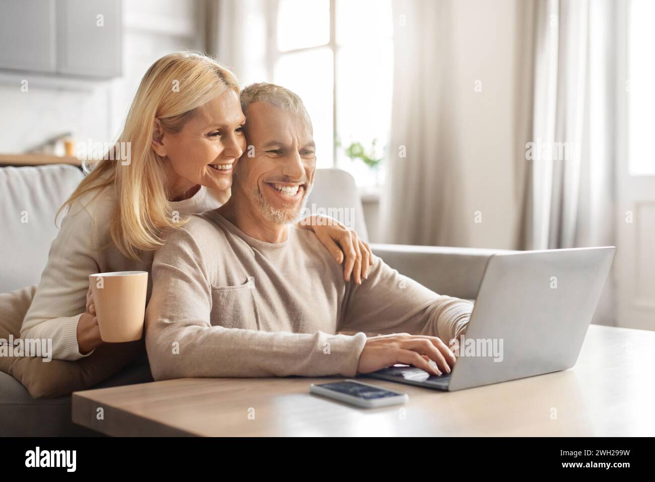 Excited smiling senior spouses using laptop computer at home Stock Photo