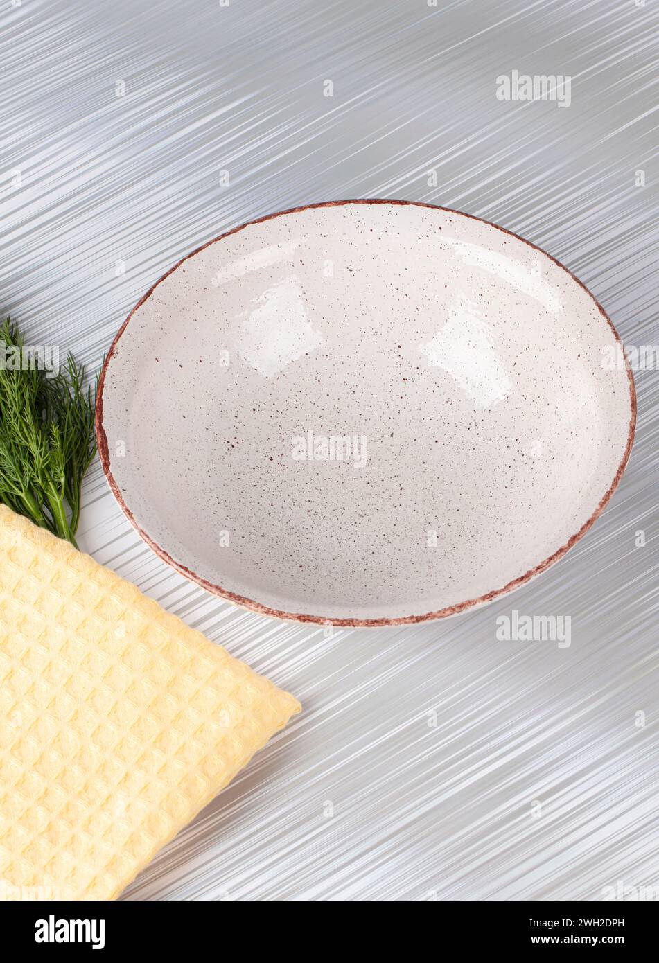 White empty deep clay plate with a spoon on a gray background. Stock Photo