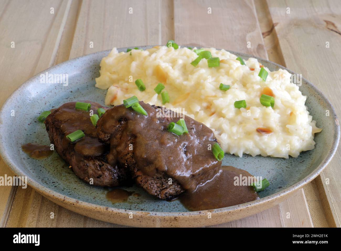 A beef fillet mignon, covered with coffee sauce, accompanied by creamy rice with almond slices. Stock Photo