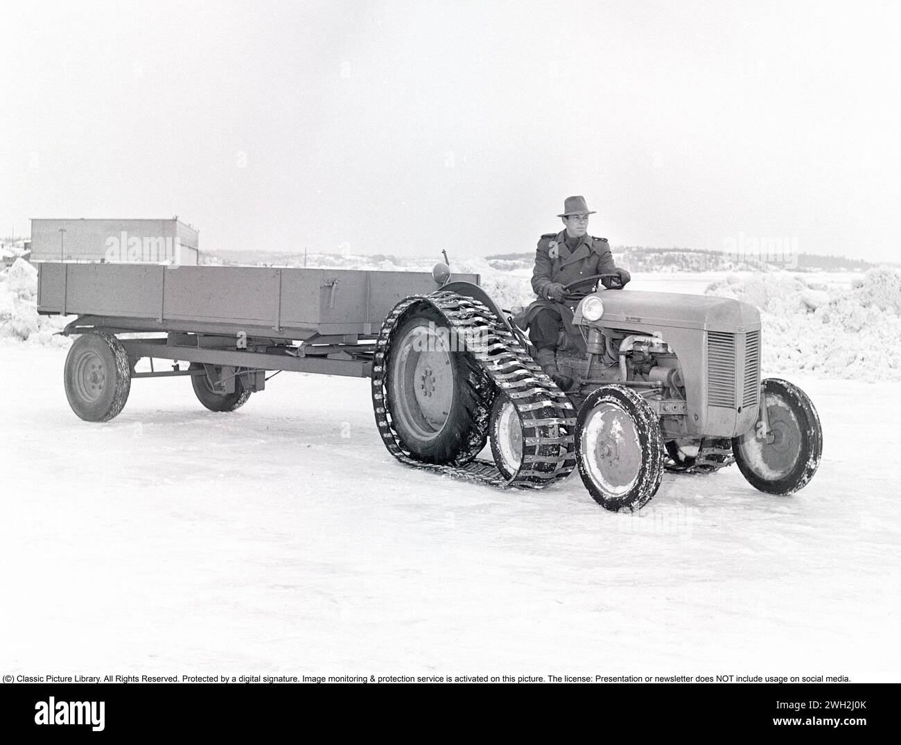 Ferguson tractor in the 1950s. A driver on the iconic Ferguson tractor featured with caterpillar bands and a one-axled wagon behind. The Ferguson tractors were the first modern agricultural tractors and its three poinkt linkage system was a major development.   1951. Kristoffersson ref BB46-4 Stock Photo