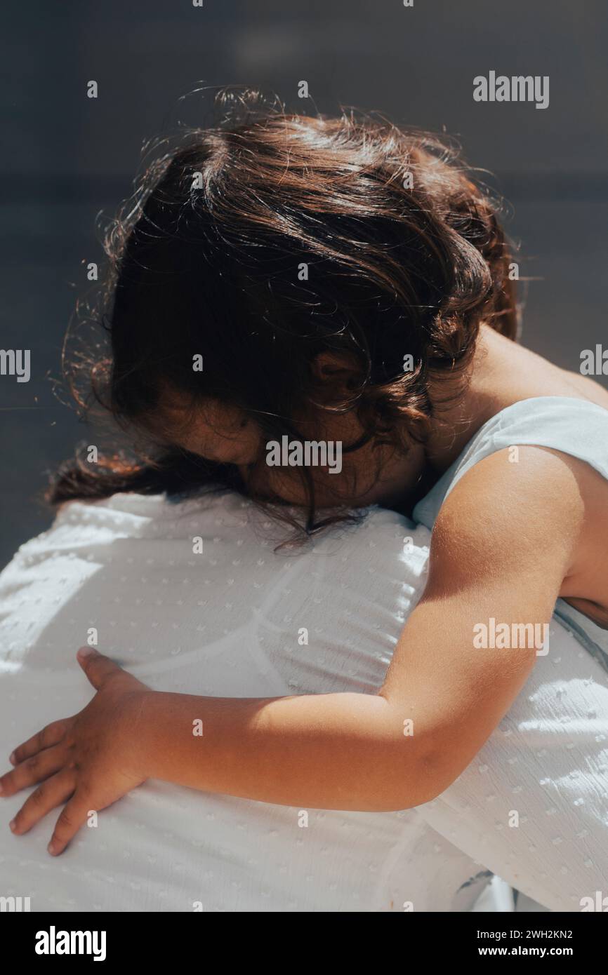 Little girl crying on her mother's shoulder Stock Photo