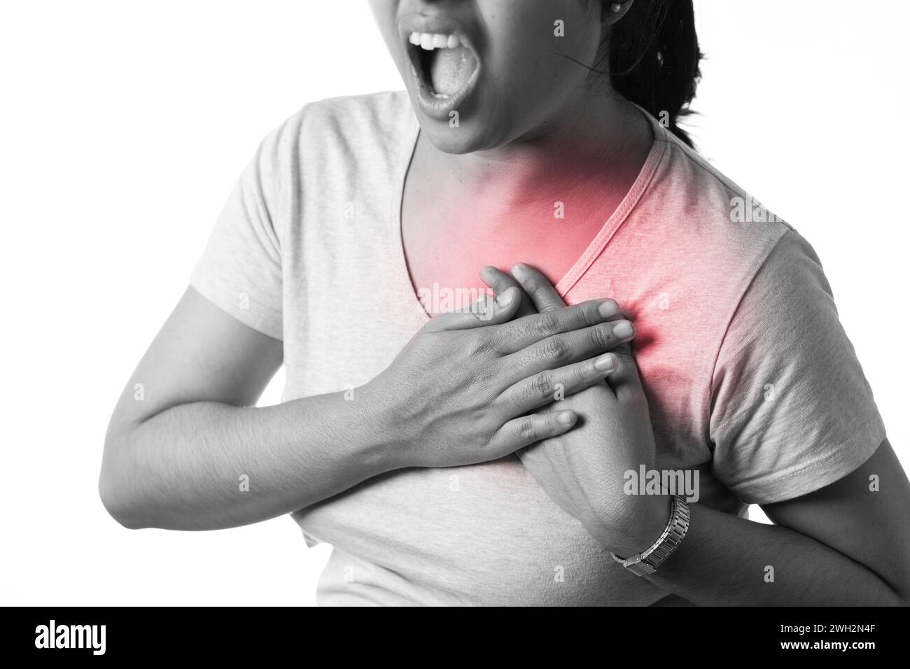 An Indian woman holding her chest for pain showing painful expression on white background Stock Photo