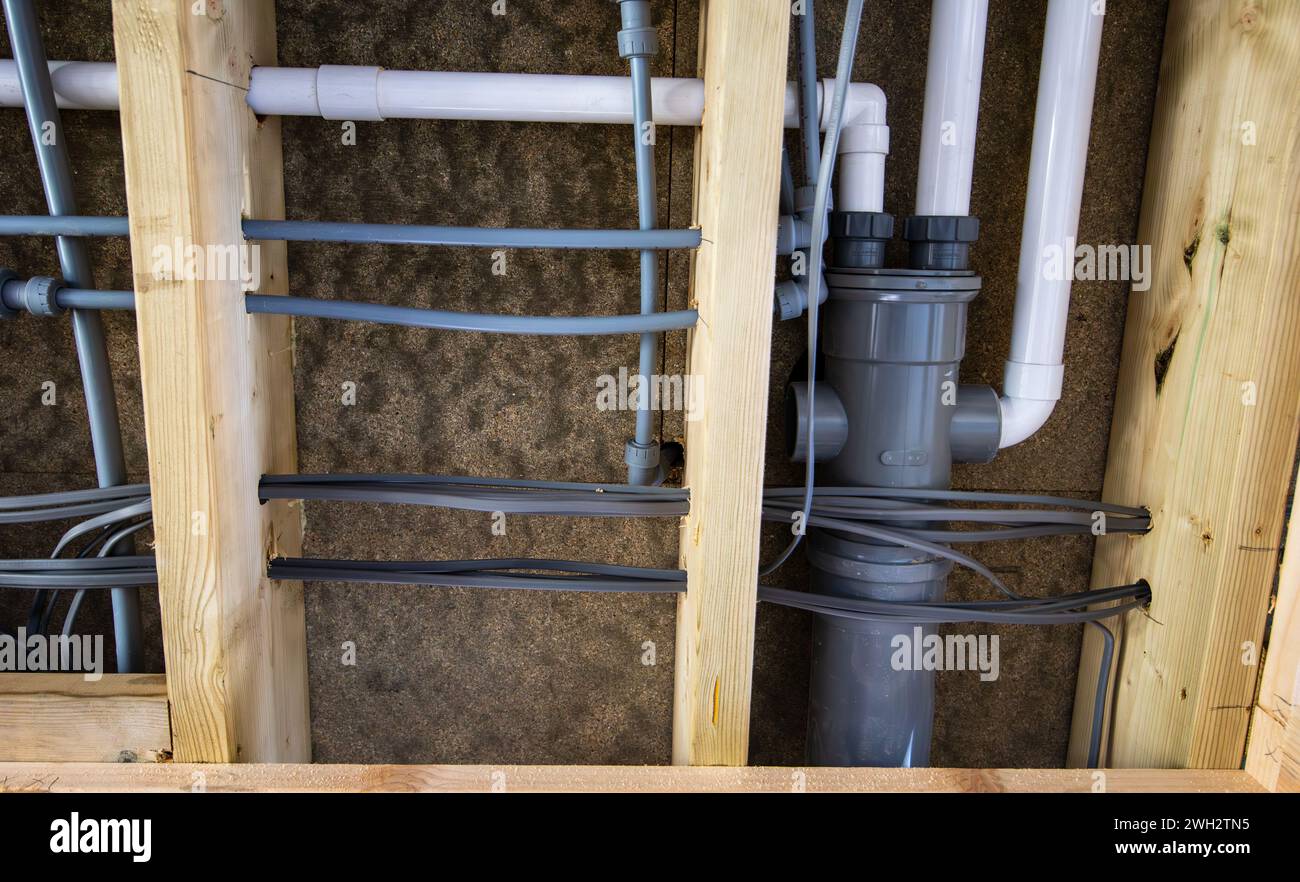 Water and waste pipes with electrical cables in ceiling joists before plasterboard ceiling is