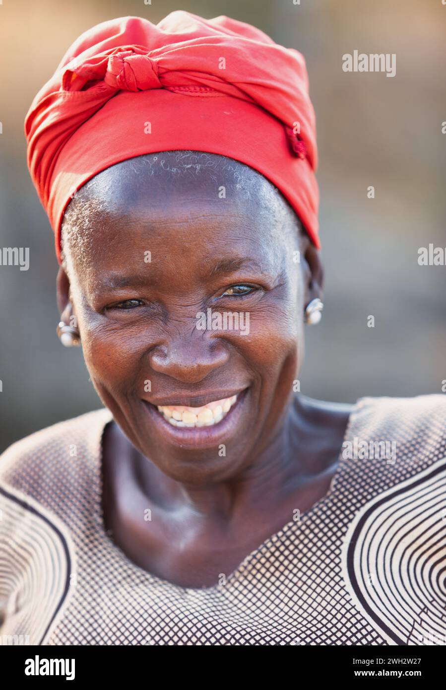 portrait of village african old woman wearing a red headscarf outdoors in the nature Stock Photo