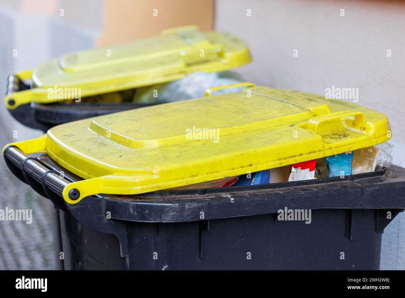 Full recycling plastic yellow packing bins with yellow lids against an ...