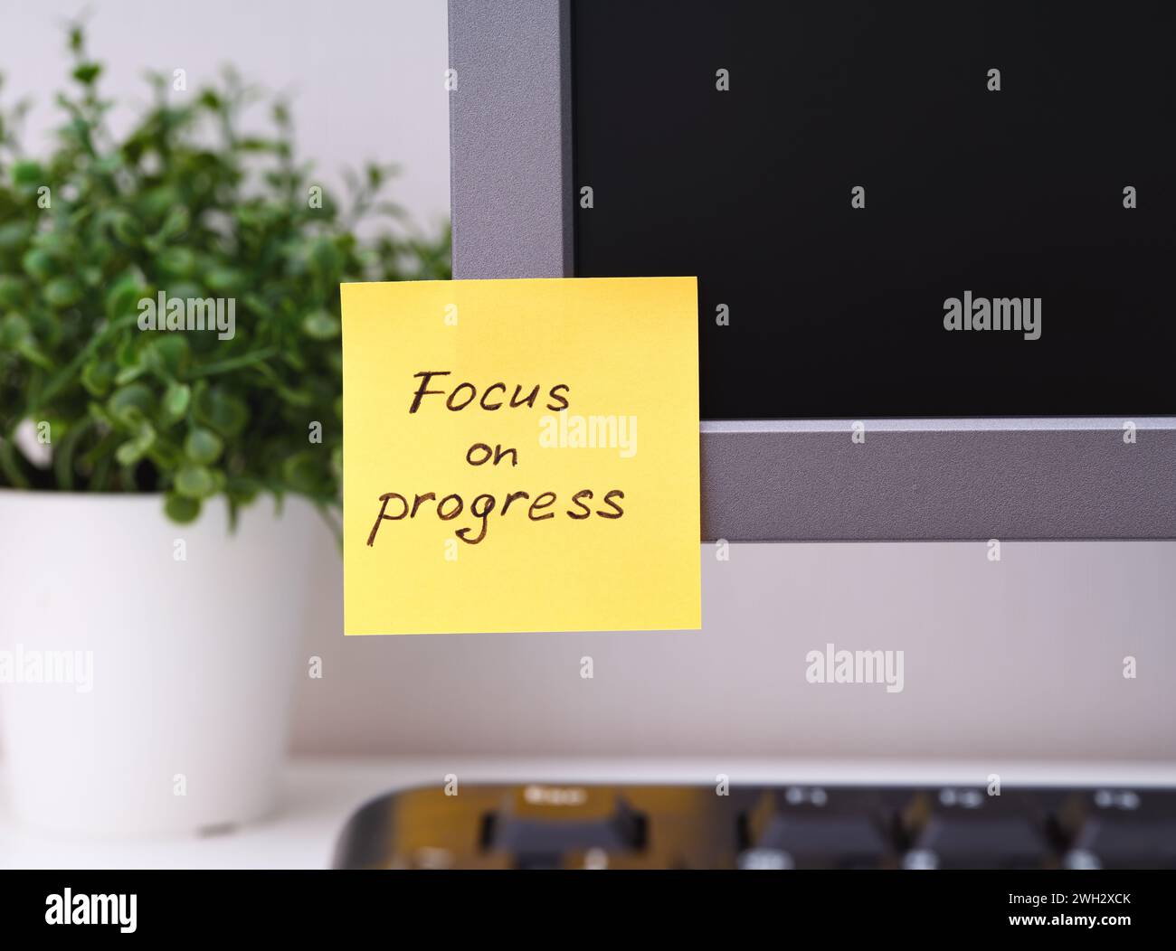 Yellow paper note with reminder Focus on Progress on it sticked on to a ...