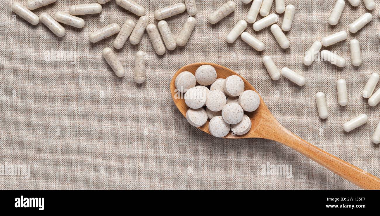 Organic dietary supplements in capsules on beige fabric background. Vitamins and natural bioadditives in tablets. Different medical pills on table. Em Stock Photo