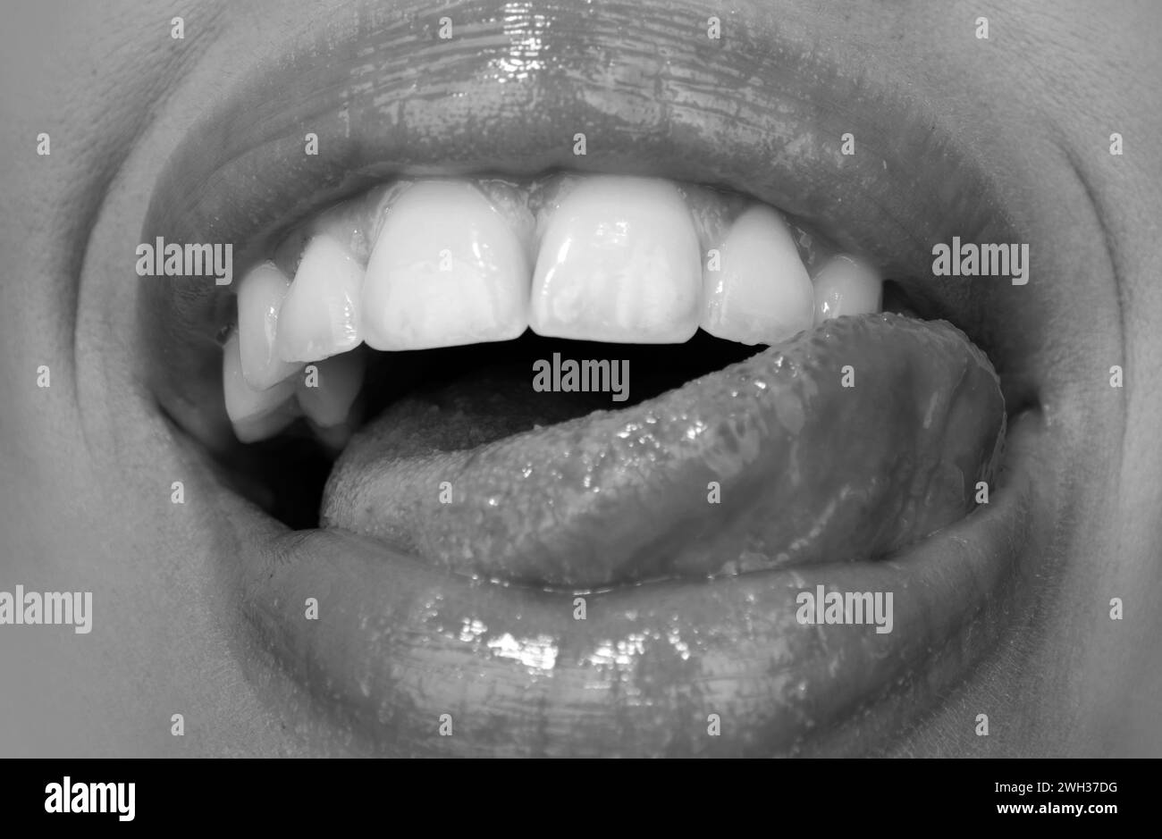 Dental care, healthy teeth and smile, white teeth in mouth. Closeup of smile with white healthy teeth. Open mouth, tongue touches the teeth. Stock Photo