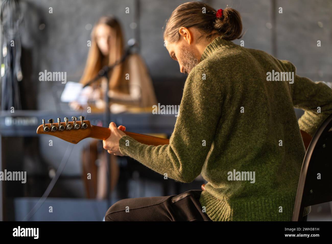 Musician sitting and entertaining event with music, playing electric guitar, plucked string instrument. Stock Photo
