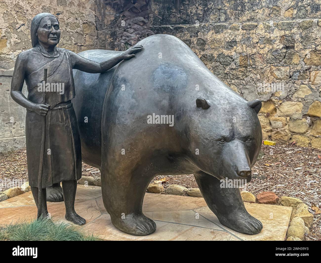 Santa Barbara, CA, USA - December 18, 2023: Chumash Memorial Bear Sculpture by Paula Zima on cemetery of Old Mission church. Image of woman with giant Stock Photo