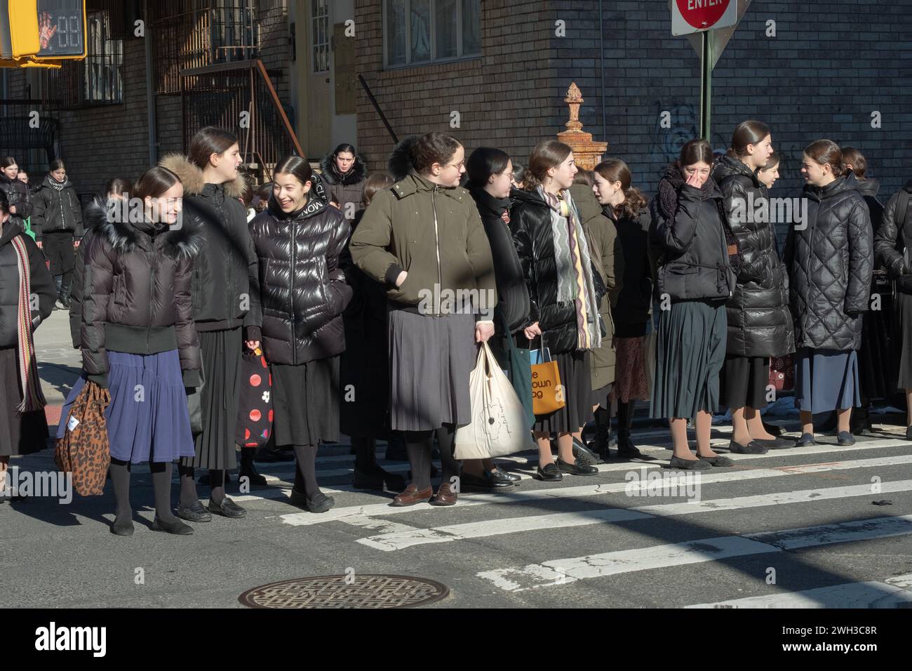 On their way to school, a large group of orthodox Jewish girls dressed modestly, wait for a light to change. In Brooklyn, New York. Stock Photo