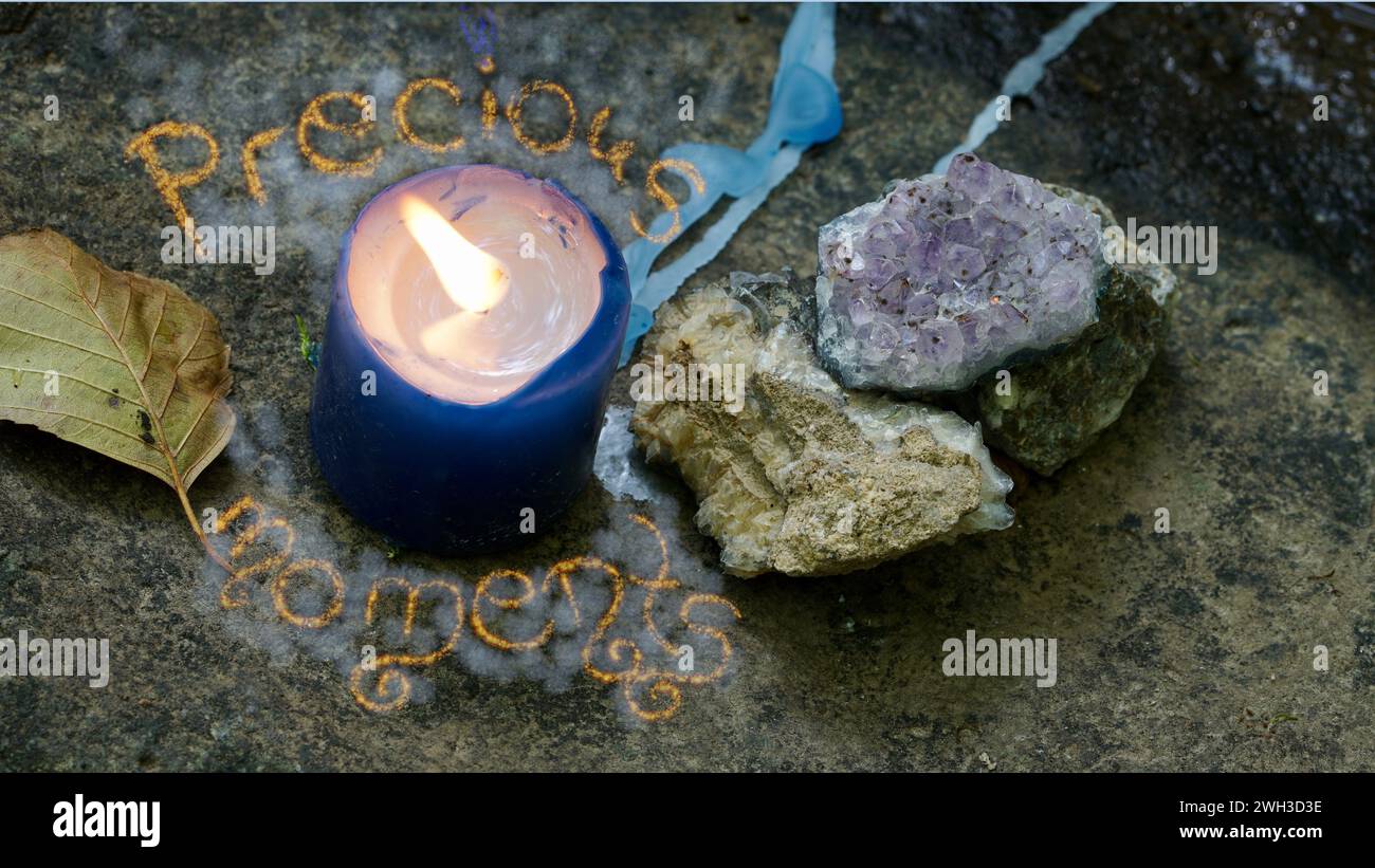 A blue candle. Gemstones next to it. Writing saying Precious moments. Concept of values in life. Stock Photo