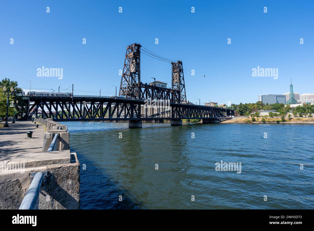 A wide-angle photo of the Portland Steel Bridge which passes over the Willamette River with a Light Rail crossing the bridge. Stock Photo