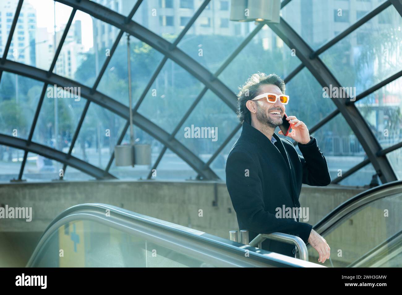 View of young man using a smartphone at indoor space with a blurred view landscape in the background. High quality photo. Talking on the phone. Stock Photo