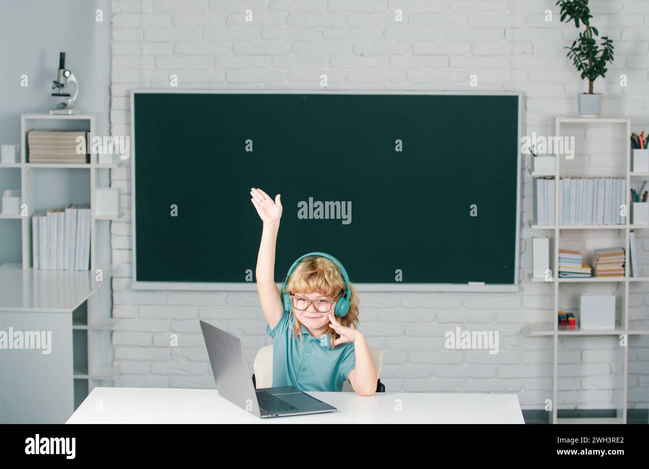 Cute little child with raised hand using laptop computer, kid boy ...