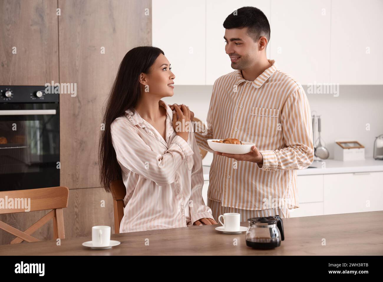 Happy young couple having breakfast in kitchen Stock Photo