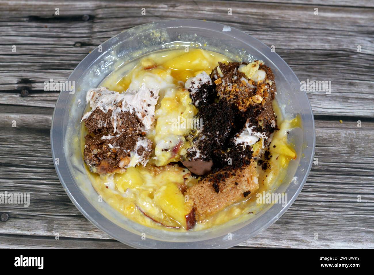 sweet mixture dessert of rice pudding, milk cream qishta, basbousa, mango juice, apple pieces, milk and sugar, with honey sugary syrup, brown, sweeten Stock Photo