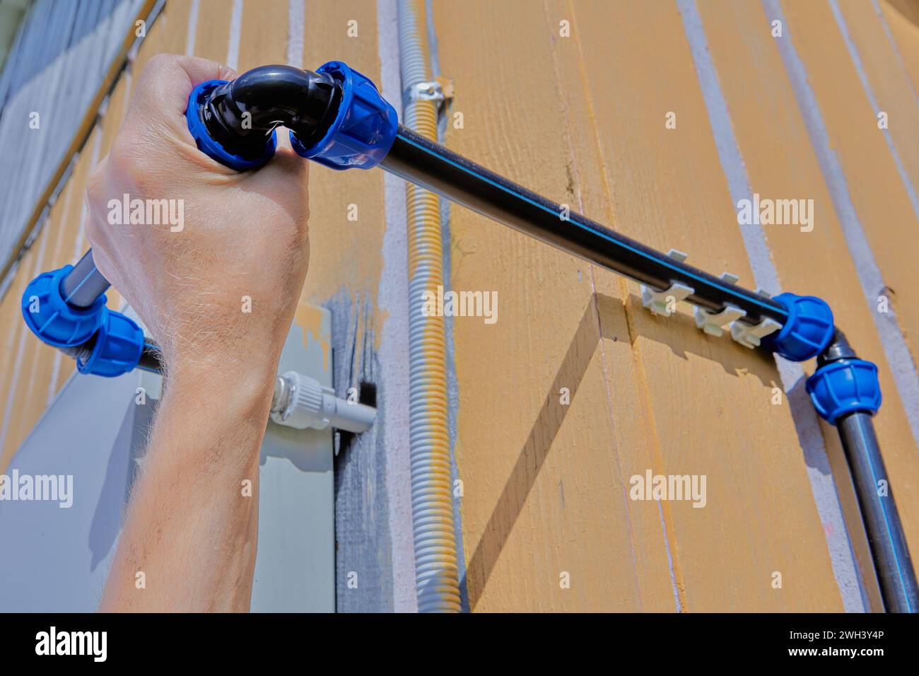 Attaching an angle pipe fitting with a compression threaded clamp to domestic outdoor water supply system for watering and irrigation, assembled from Stock Photo