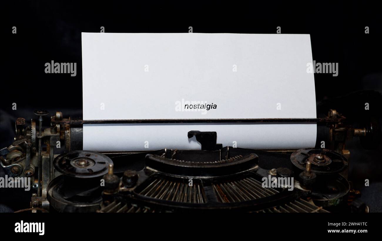 An old rusty typewriter with paper. Nostalgia written on the paper. Concept of memories, nostagia, old times. Stock Photo